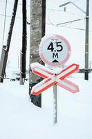 deténgase. la señal de carretera roja se encuentra en la autopista que cruza la línea ferroviaria en la temporada de invierno foto