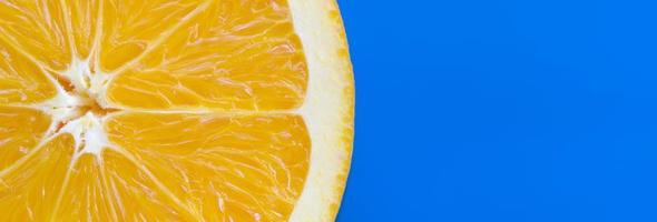 Top view of a one orange fruit slice on bright background in blue color. A saturated citrus texture image photo