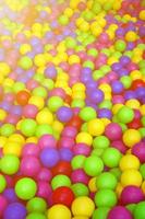 Many colorful plastic balls in a kids' ballpit at a playground. Close up pattern photo