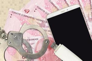 10 Turkish liras bills and smartphone with police handcuffs. Concept of hackers phishing attacks, illegal scam or malware soft distribution photo