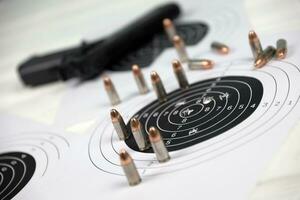 Gun and many bullets shooting targets on white table in shooting range polygon. Training for aiming and shooting photo