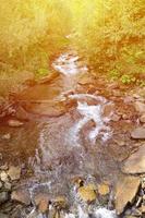 Close-up image of a small wild waterfall in the form of short streams of water between mountain stones photo