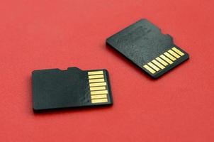 dos pequeñas tarjetas de memoria micro sd se encuentran sobre un fondo rojo. un pequeño y compacto almacén de datos e información foto