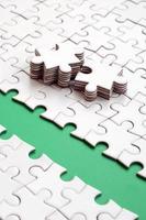 The green path is laid on the platform of a white folded jigsaw puzzle. The missing elements of the puzzle are stacked nearby. Texture image with space for text photo