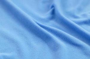 The blanket of furry blue fleece fabric. A background of light blue soft plush fleece material with a lot of relief folds photo