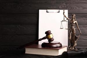 Lady justice or justitia the Roman goddess of Justice. Statue on brown book with judge gavel on blank paper background with copyspace. Concept of judicial trial, courtroom process and lawyers work photo