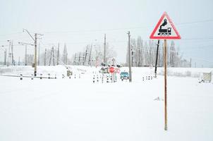 cruce ferroviario sin barrera con muchas señales de advertencia en la temporada de invierno con nieve foto