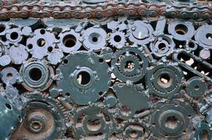 A composition of a set of gears and car parts that are welded to each other and painted green. Grunge steampunk texture photo