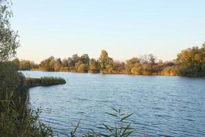 hermoso paisaje otoñal con lago y árboles multicolores. lugar pintoresco con lago y árboles altos foto