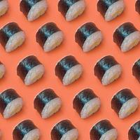 Classic black sushi rolls on bright orange background photo