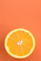 Top view of a one orange fruit slice on bright background in orange color. A saturated citrus texture image photo