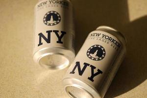 TERNOPIL, UKRAINE - JULY 18, 2022 Two cans of New Yorker fine lager beer with original logo and design on brown retro background photo