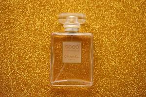 TERNOPIL, UKRAINE - SEPTEMBER 2, 2022 Coco Mademoiselle Chanel Paris worldwide famous french perfume bottle on shiny glitter background in golden colors photo