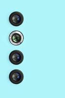 A few camera lenses with a closed aperture lie on texture background of fashion pastel blue color paper photo