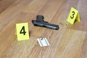 Crime scene investigation concept - Pistol and bullet shell against the yellow crime marker on apartment floor photo