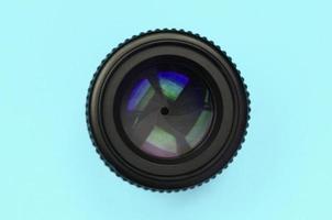 Camera lens with a closed aperture lie on texture background of fashion pastel blue color paper photo