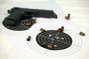 pistola y muchas balas disparando objetivos en la mesa blanca en el polígono de campo de tiro. entrenamiento para apuntar y disparar foto