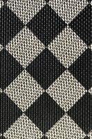 Plastic texture in the form of a very small cloth binding, painted in black and gray in the style of a chessboard. Macro shot photo