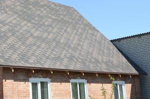 Flexible shingles of bitumen roofing surface on the brick house photo