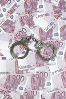 Handcuffs on five hundred euros background. Financial crime, dirty money and corruption concept - 500 money bills and dirty steel handcuffs photo