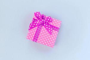 Small purple gift box with ribbon lies on a violet background photo