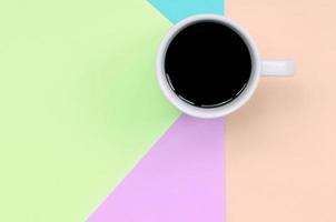 Small white coffee cup on texture background of fashion pastel pink, blue, coral and lime colors paper photo