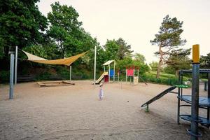 Baby girl in children's playground toy set in public park. photo