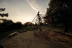 Silhouettes of children play in rope polyhedron climb at playground outdoor. photo