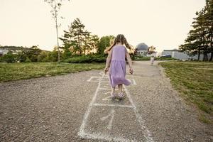 Two sisters playing hopscotch in park. Kids game, children outdoor activities. photo