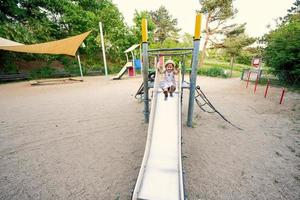 Baby girl slides in children's playground toy set in public park. photo