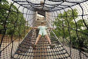 Boy playing in rocket slide ropes at children's playground in public park. photo