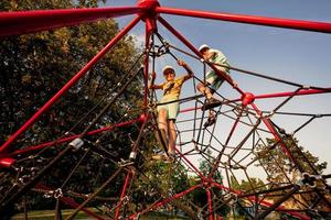 Brothers play in rope polyhedron climb at playground outdoor. photo