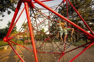 los hermanos juegan en la escalada de poliedro de cuerda en el patio de recreo al aire libre. foto