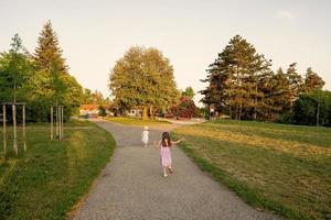 Back of two sisters run to playground in park. photo