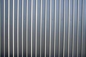 Corrugated metal sheet fence with natural grainy texture photo