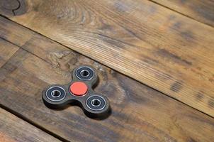 A rare handmade wooden fidget spinner lies on a brown wooden background surface. Trendy stress relieving toy photo