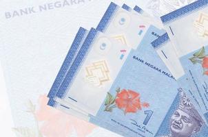 1 Malaysian ringgit bills lies in stack on background of big semi-transparent banknote. Abstract presentation of national currency photo