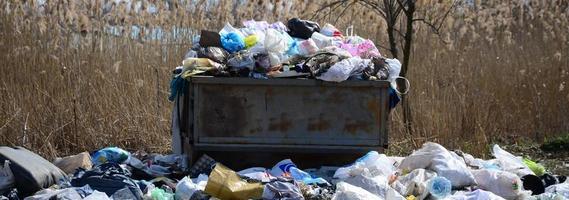 el bote de basura está lleno de basura y desechos. retiro intempestivo de basura en zonas pobladas foto