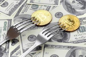 Bitcoin getting New Hard Fork Change, Physical Golden Crytocurrency Coin under the fork on the dollars background. Blockchain Transaction System Crisis Concept photo