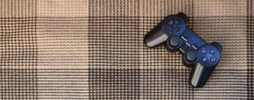 Video game controller lies on a checkered plaid photo