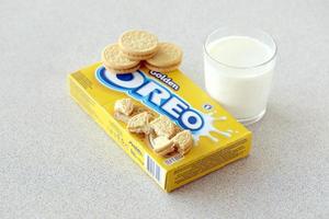 TERNOPIL, UKRAINE - MAY 28, 2022 Oreo golden crispy cookies with glass of milk on white background. The brand Oreo is owned by company Mondelez international photo