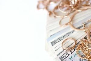 Many expensive golden jewerly rings, earrings and necklaces with big amount of US dollar bills on white background. Pawnshop or jewerly shop photo