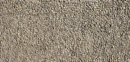 Texture of a stone wall with small round pebble stones. Part of a stone wall as a background or texture photo
