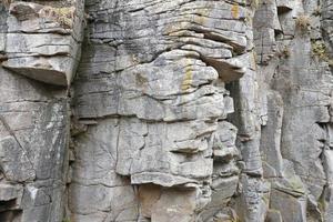 Light coarse natural rock stone background. Mining cliff rough front surface. Big limestone stack backdrop. Heavy grunge damaged granite block texture photo