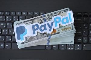 TERNOPIL, UKRAINE - SEPTEMBER 6, 2022 Payoneer paper logotype lies on black laptop with US dollar bills. Payoneer is American financial services company provides online money transfer photo