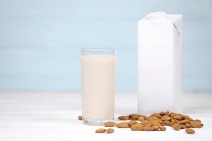 Glass of almond milk with almond nuts on canvas fabric on white wooden table. Dairy alternative milk for detox, healthy eating and diets photo