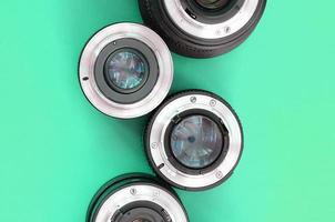 Several photographic lenses lie on a bright turquoise background. Copy space photo