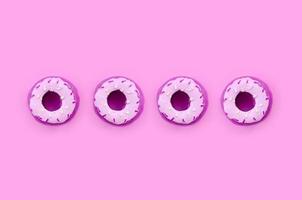 Many small plastic donuts lies on a pastel colorful background. Flat lay minimal pattern. Top view photo