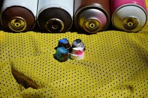 Several caps for used aerosol paint sprayers lie on the sports shirt of a basketball player made of polyester fabric. The concept of youth street art, active sports and eventful lifestyle photo