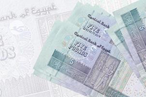 5 Egyptian pounds bills lies in stack on background of big semi-transparent banknote. Abstract presentation of national currency photo